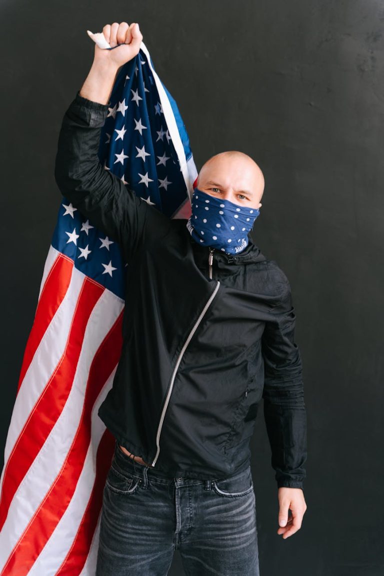photo of a man in a black jacket holding a united states of america flag
