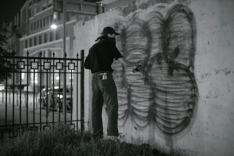 a person standing near the wall while using spray paint