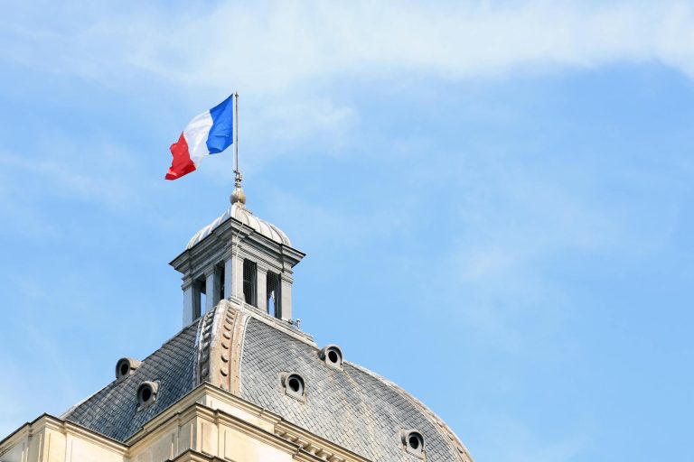 french flag atop historic parisian building